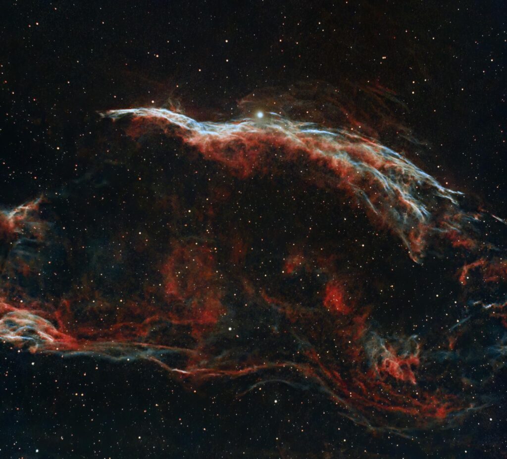 Explore the vibrant colors and patterns of the Veil Nebula captured in deep space.