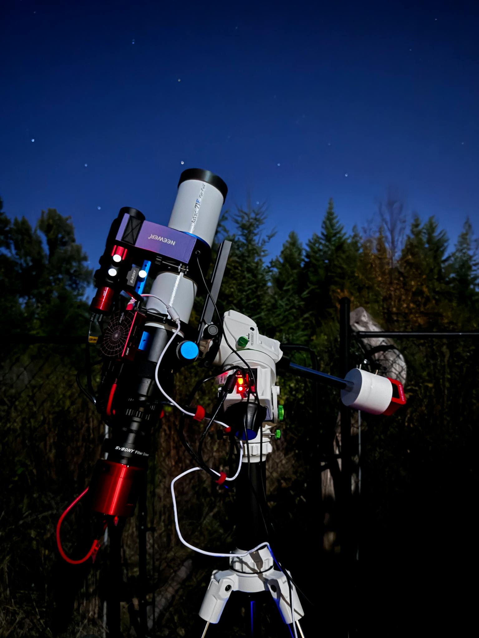 Modern telescope setup for stargazing in a serene nighttime forest.